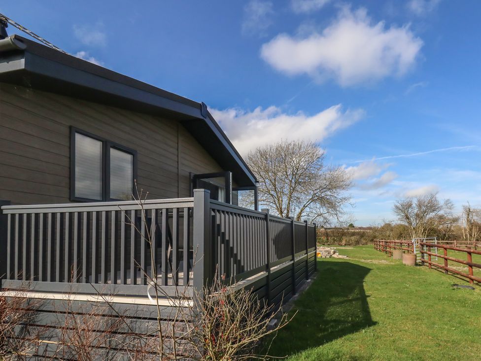 A house with a deck and fencing on a lawn at Grass Roots