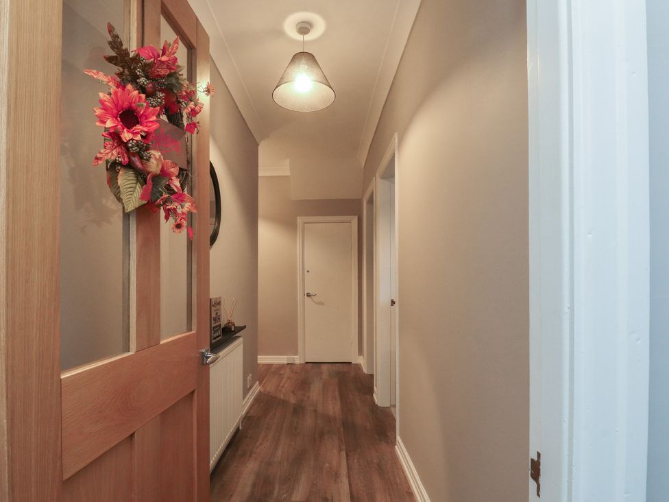 A hallway with a door, a mirror, and a light fixture at Flat 6 in Lytham St. Annes