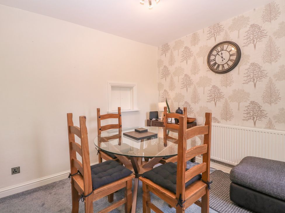 A dining room with a glass table and wooden chairs at 24 Cefn Court Newport