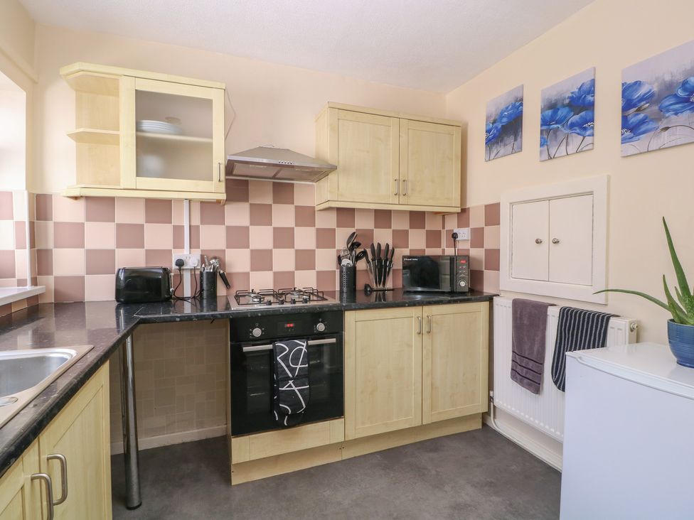 A kitchen with cabinets and appliances at 24 Cefn Court in Newport