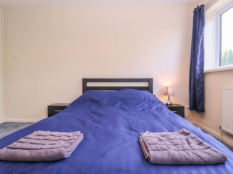 A bedroom with a bed and nightstand at 24 Cefn Court Newport