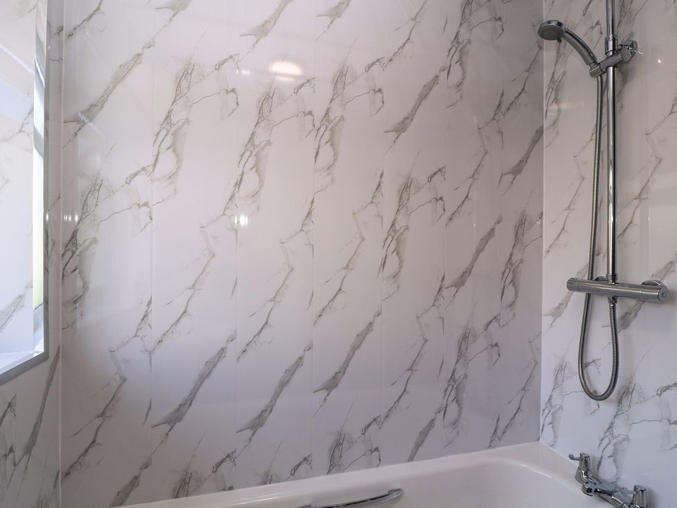 A bathroom with a shower and tub at 24 Cefn Court Newport