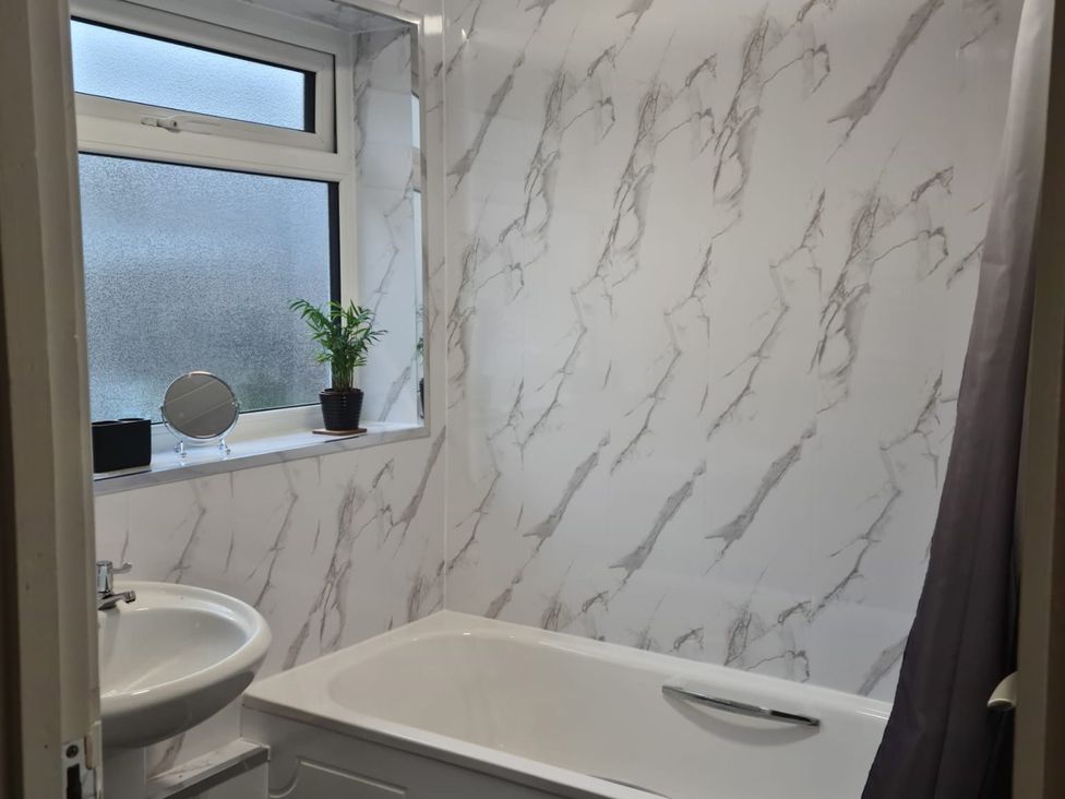 A bathroom with a bathtub and sink at 24 Cefn Court in Newbridge, Caerffili