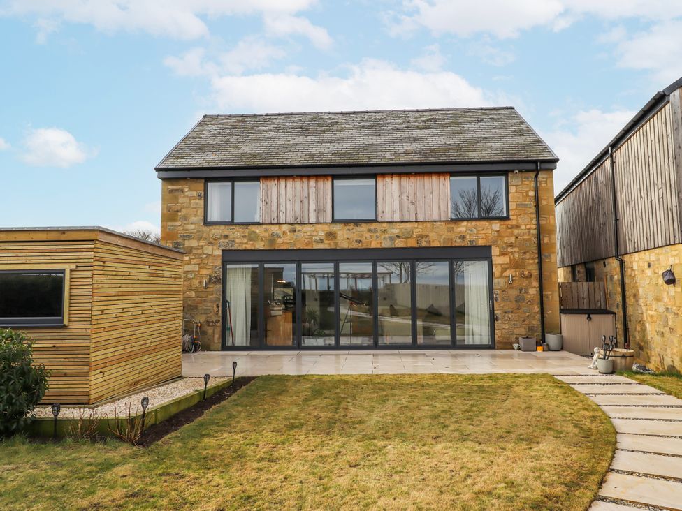 A house with windows and doors on a patio at The Joiners Cottage in Birling near Warkworth