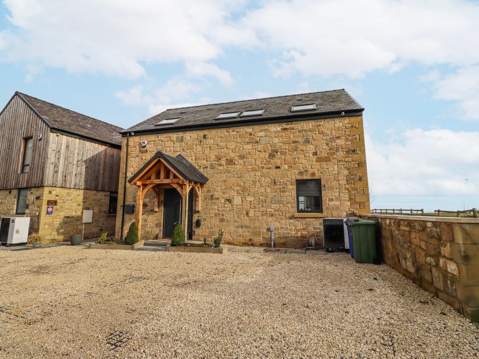 An outdoor view of a stone building with a gravel area at The Joiners Cottage in Birling near Warkworth
