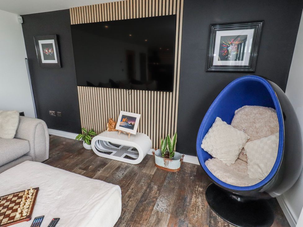 A living room with a television and egg chair at The Joiners Cottage in Birling near Warkworth