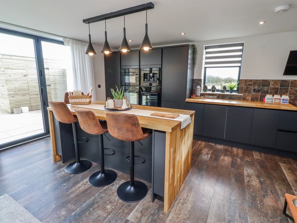 A kitchen with a large island and bar stools at The Joiners Cottage in Birling near Warkworth