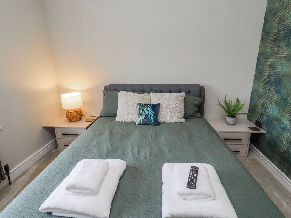 A bedroom with a bed and lamp at The Joiners Cottage in Birling near Warkworth