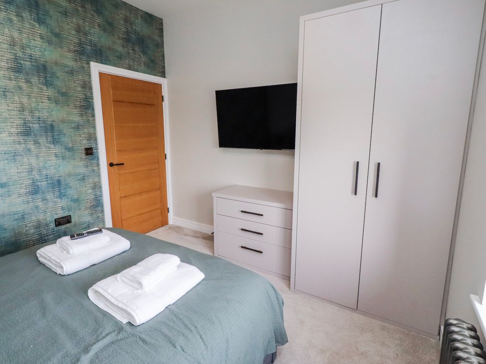A bedroom with a bed and a wardrobe at The Joiners Cottage in Birling near Warkworth