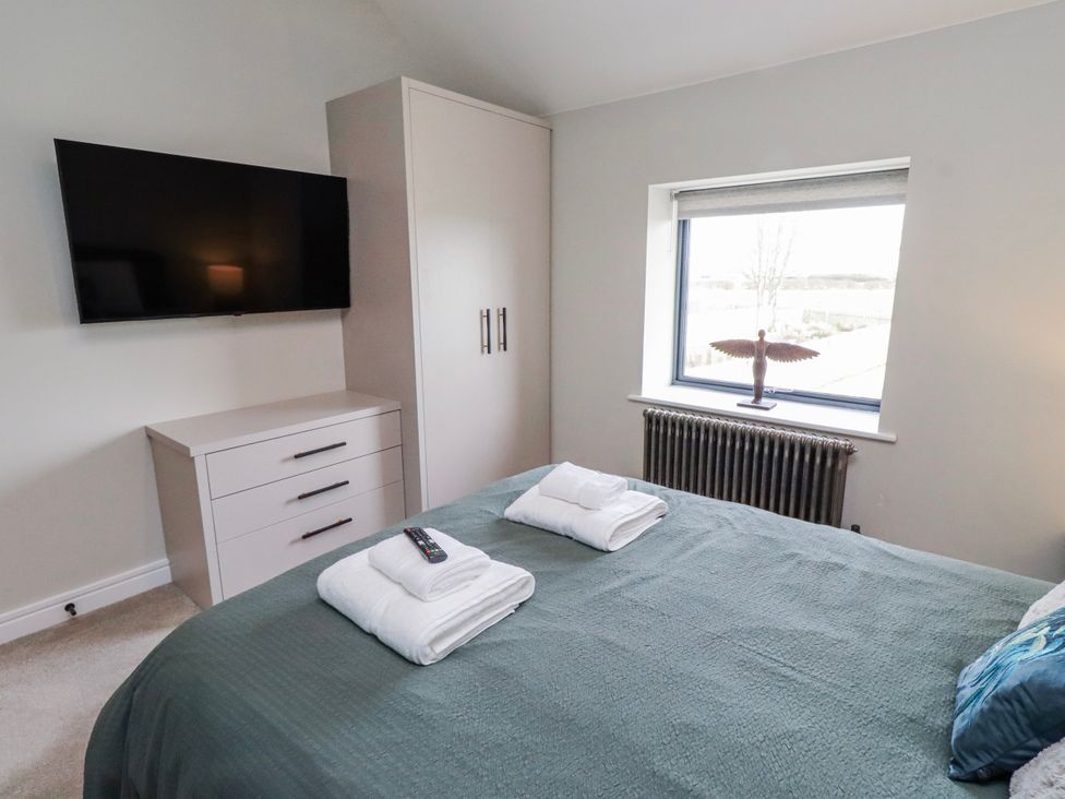 A bedroom with a bed and television at The Joiners Cottage in Birling near Warkworth