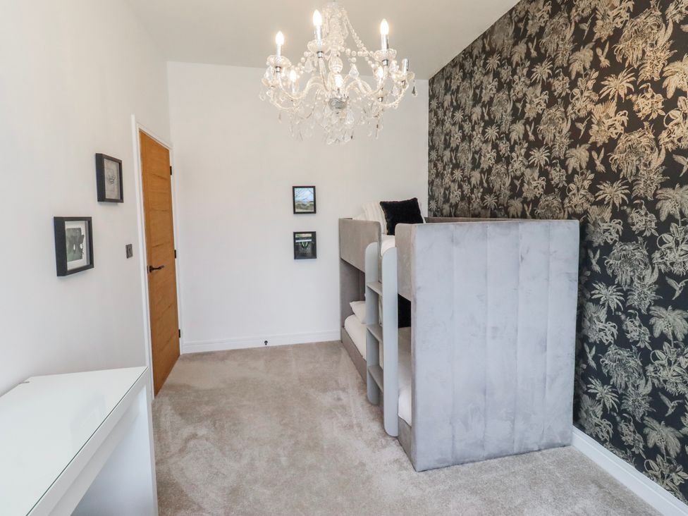 A bedroom with shelves and a chandelier at The Joiners Cottage in Birling near Warkworth