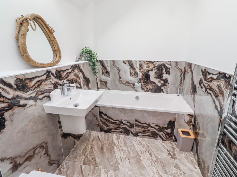 A bathroom with a bathtub and sink at The Joiners Cottage in Birling near Warkworth