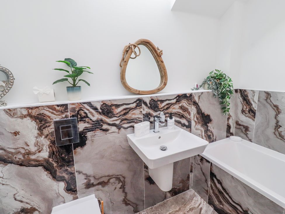 A bathroom with a sink and bathtub at The Joiners Cottage in Birling near Warkworth
