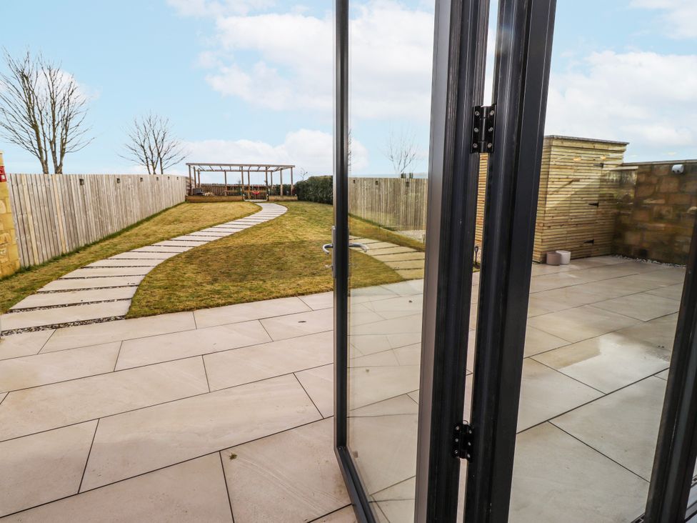 A garden with a pathway and seating area at The Joiners Cottage Birling near Warkworth