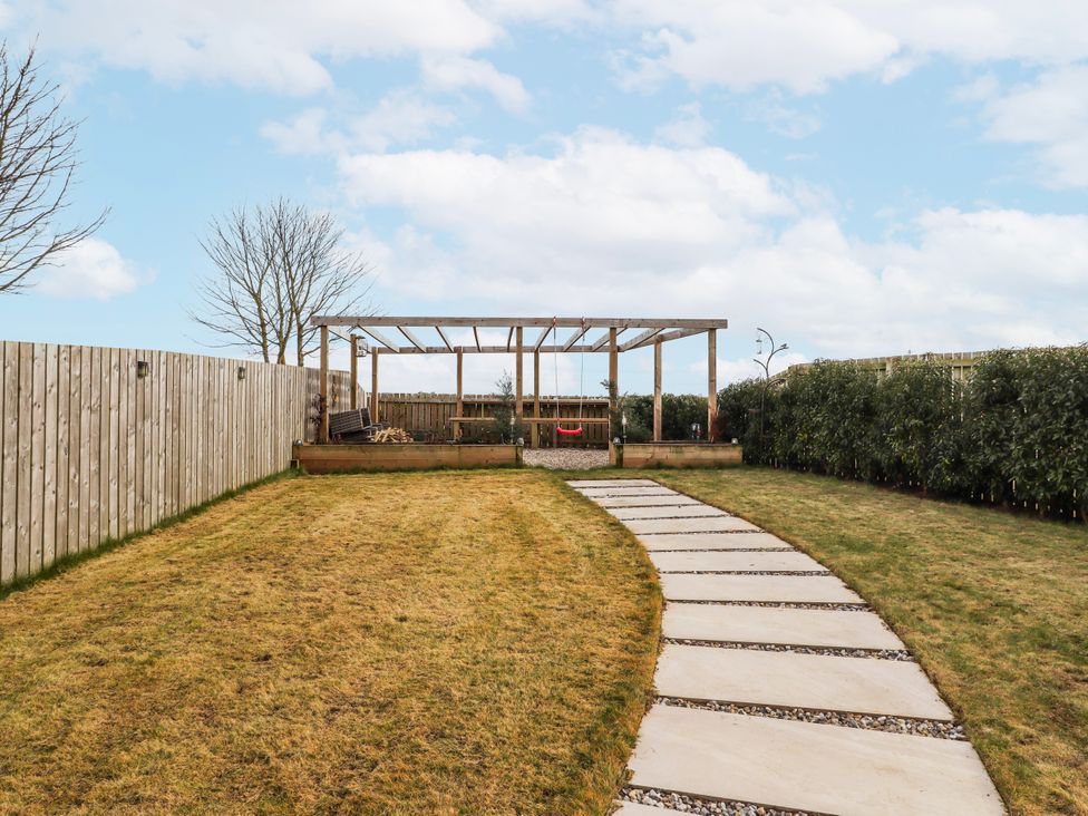 A garden with a path leading to a pergola at The Joiners Cottage Birling near Warkworth