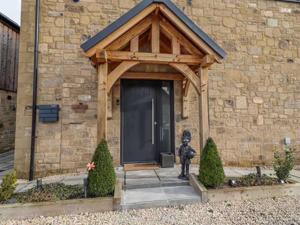 An entrance with a door, statue, and plants at The Joiners Cottage in Birling near Warkworth