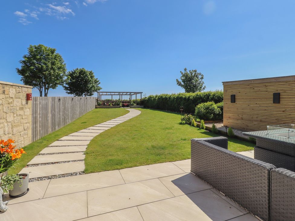 A garden with a pathway and seating area at The Joiners Cottage in Birling near Warkworth