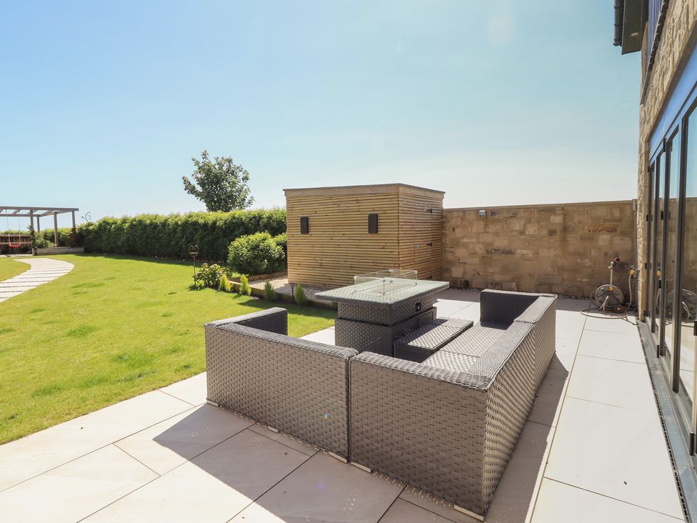 A garden with outdoor seating and a shed at The Joiners Cottage in Birling near Warkworth