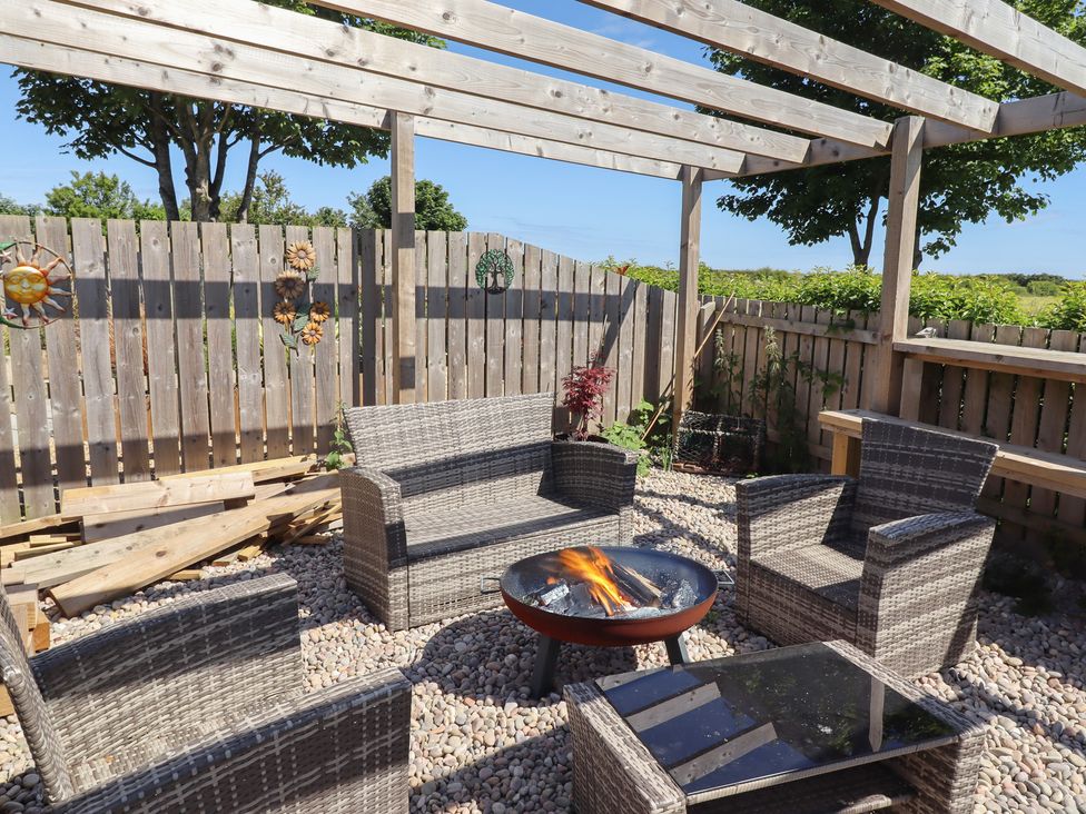 An outdoor seating area with a fire pit and gravel surface at The Joiners Cottage in Birling near Warkworth
