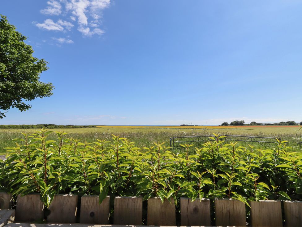A view of a field and sky from a wooden fence at The Joiners Cottage in Birling near Warkworth