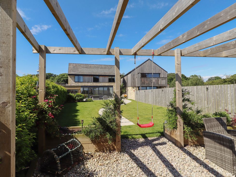 A garden with a swing and pathway at The Joiners Cottage in Birling near Warkworth