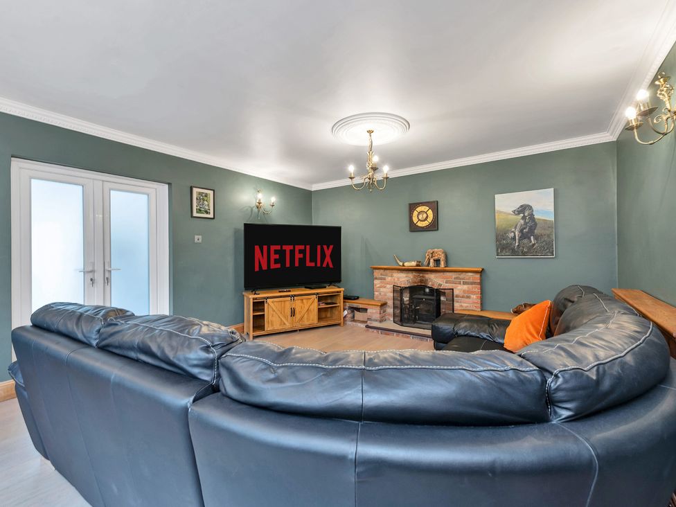A living room with a TV showing Netflix and a fireplace at Oldfields