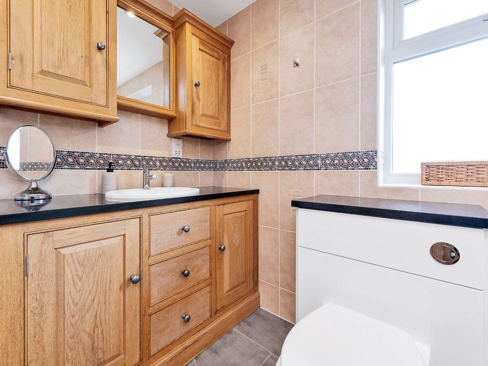 A bathroom featuring a mirror, sink, cabinet, and toilet at Oldfields
