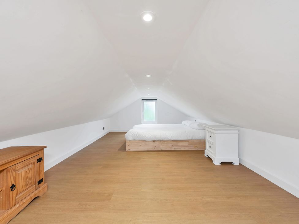 An attic space with a bed and nightstand at Oldfields