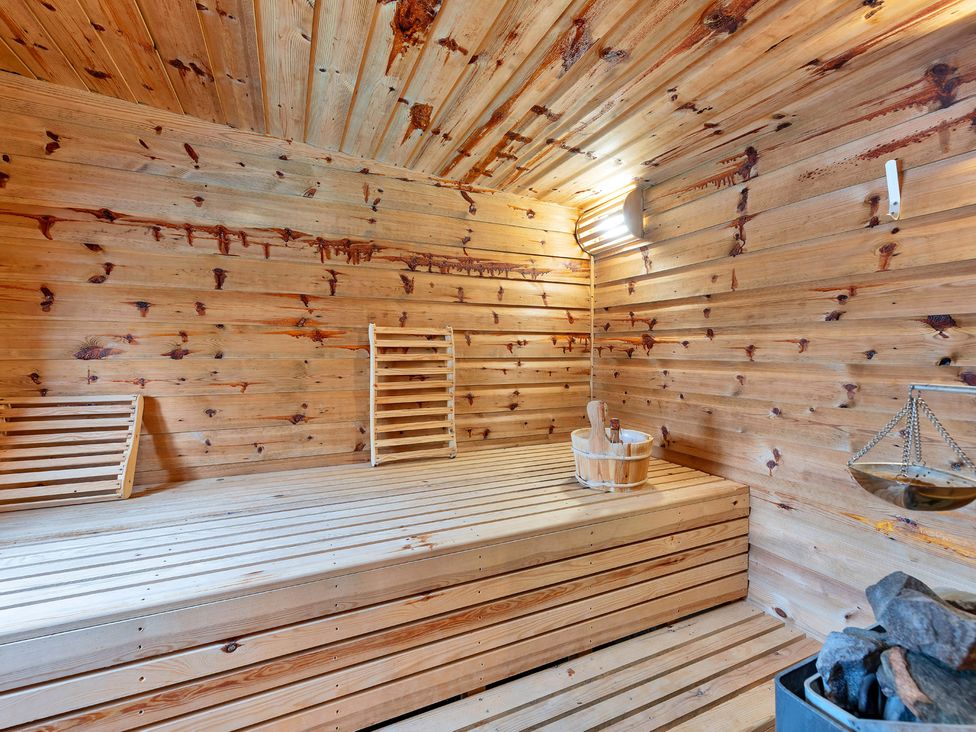 A sauna with wooden benches and a bucket at Oldfields