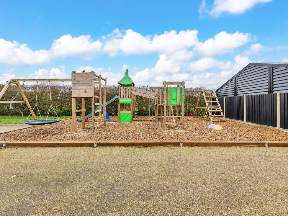 An outdoor play area with swings and climbing frames at Oldfields