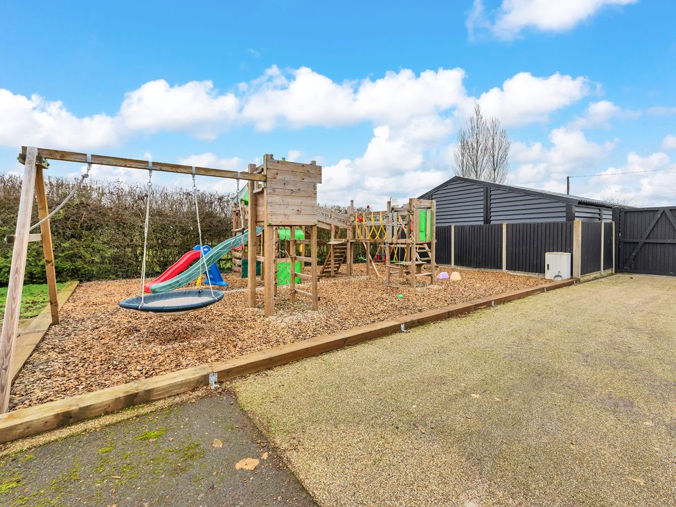 An outdoor play area with a playground featuring swings and a slide at Oldfields
