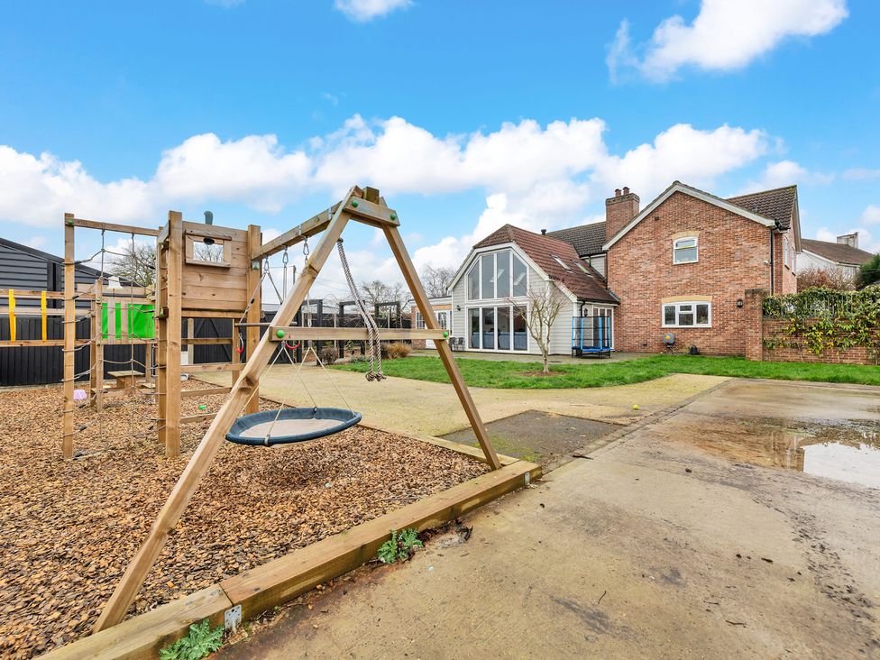 A playground area with a swing and house in the background at Oldfields