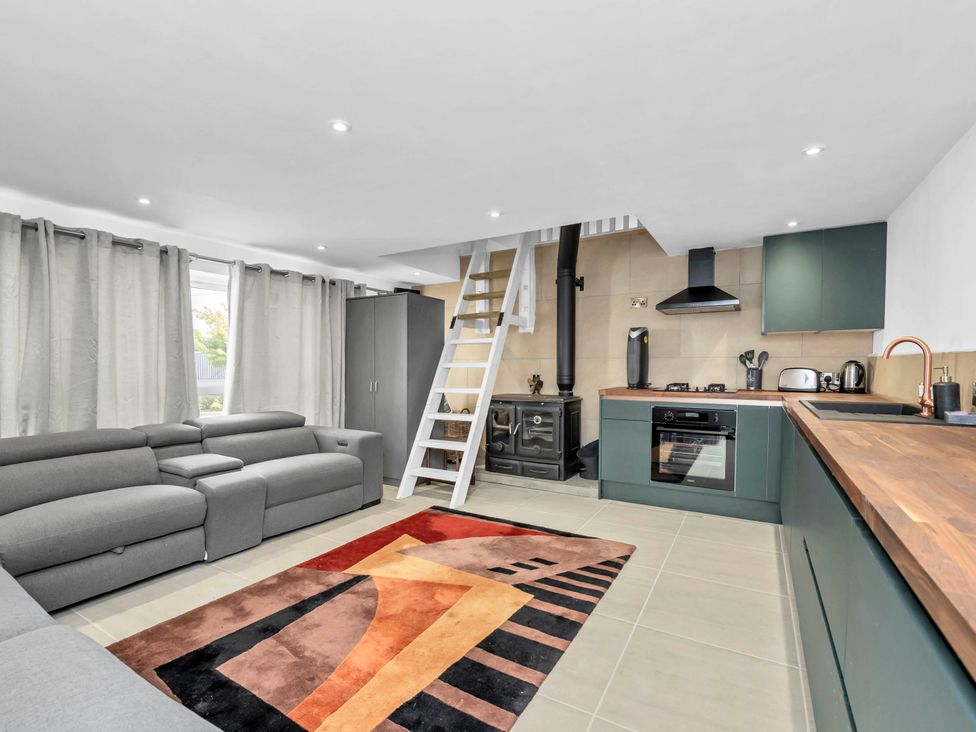 A living room with a sofa and kitchen area at Oldfields in Bury St Edmunds