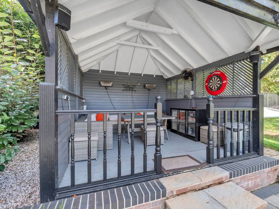 An outdoor seating area with a darts board and sofa at Oldfields in Bury St Edmunds