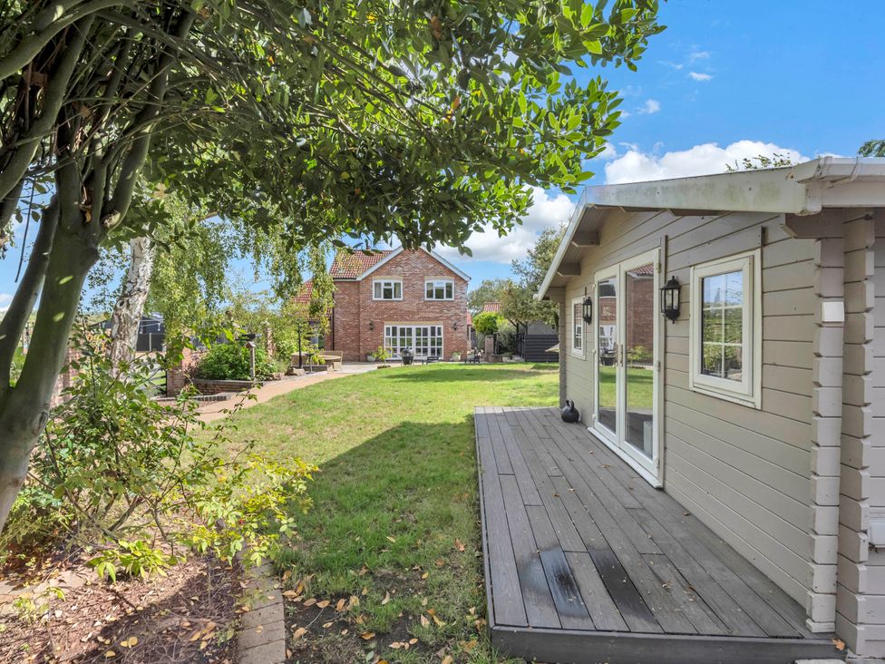 A garden with a deck and house in the background at Oldfields in Bury St Edmunds