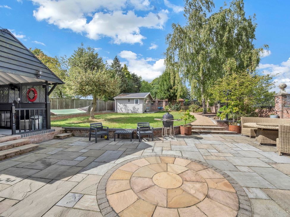 A garden with a patio, seating area, and shed at Oldfields in Bury St Edmunds