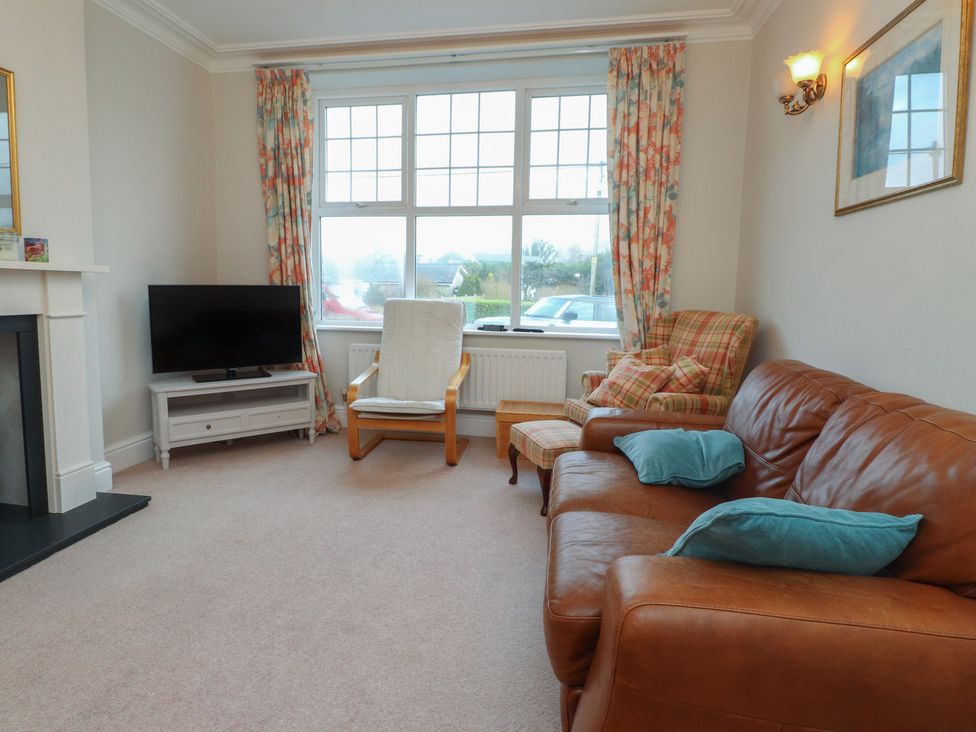 A living room with a sofa and television at Bryniau in Pwllheli