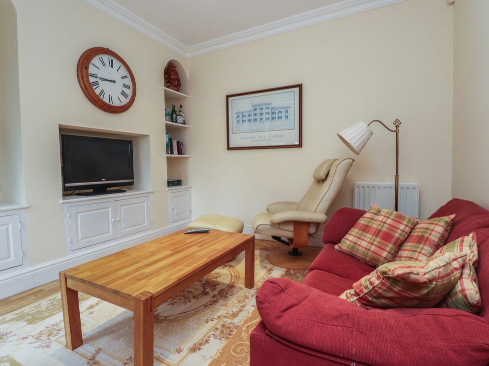 A living room with a sofa, table, and television at Bryniau in Pwllheli