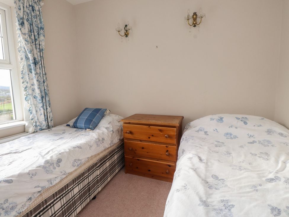 A bedroom with two beds and a dresser at Bryniau in Pwllheli