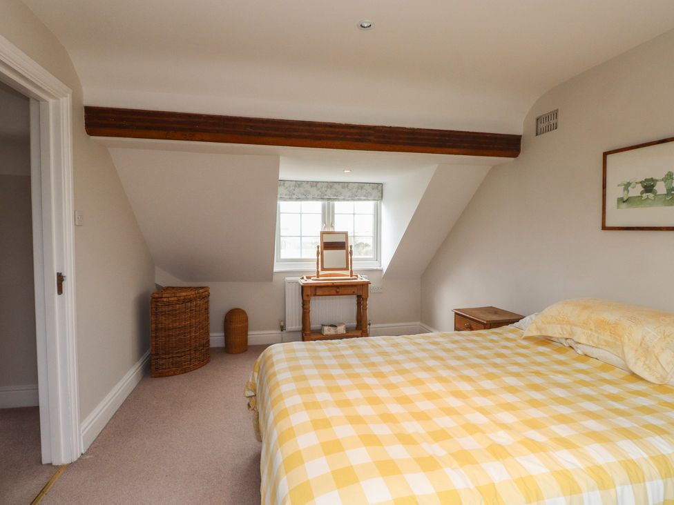 A bedroom with a bed, mirror, and wicker basket at Bryniau in Pwllheli