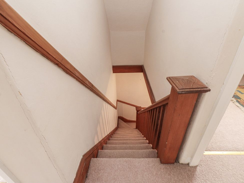 A staircase with wooden handrail and carpet at Bryniau Pwllheli