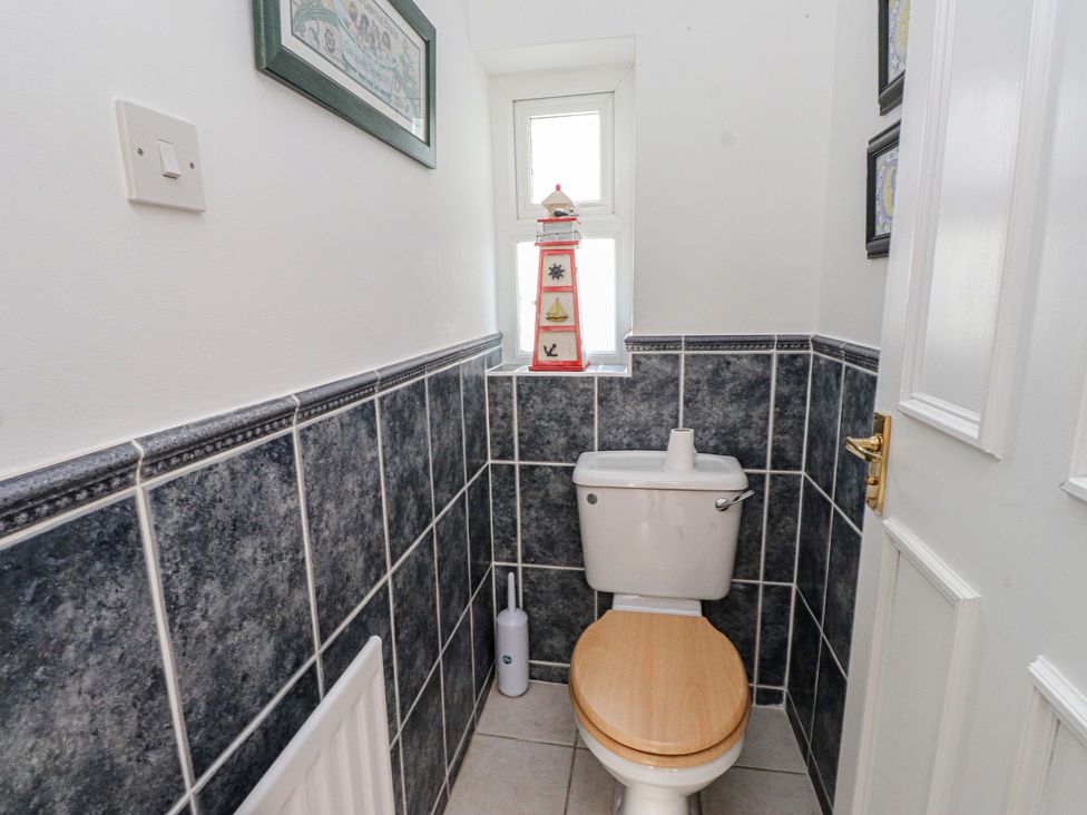 A bathroom with a toilet and framed pictures at Bryniau in Pwllheli