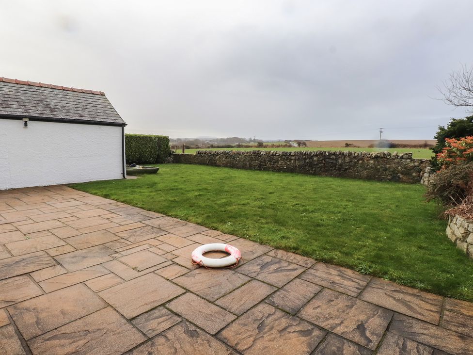A garden with grass and stone paving at Bryniau Pwllheli