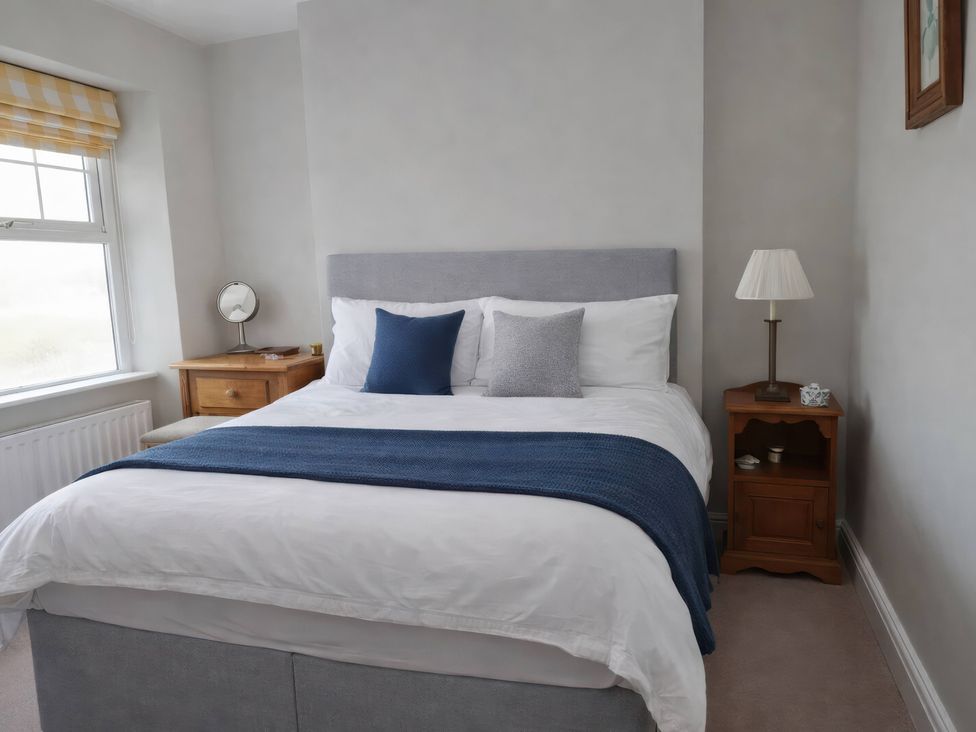 A bedroom with a bed, bedside table and lamp at Bryniau in Morfa Nefyn