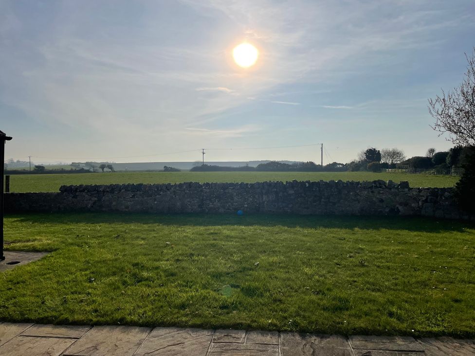 A sunny view of a field and stone wall at Bryniau in Morfa Nefyn