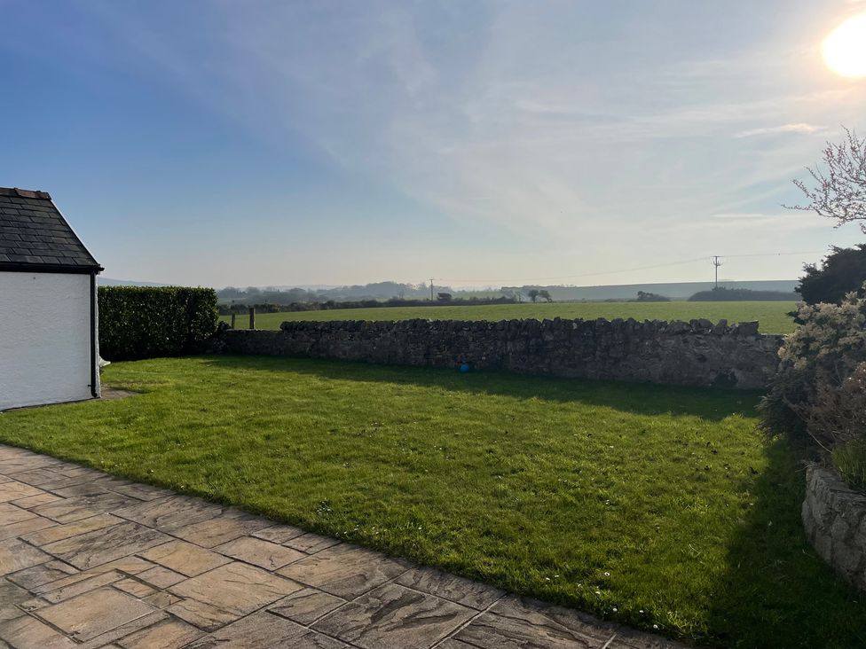A garden with grass and stone wall at Bryniau in Morfa Nefyn
