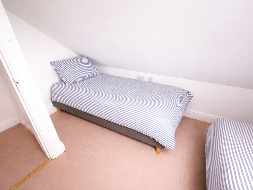 A bedroom with two beds and a door at Bryniau, Morfa Nefyn