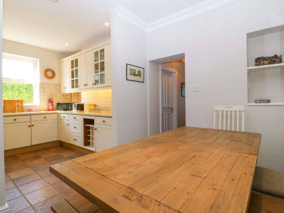 A kitchen with a dining table and cabinetry at Bryniau in Morfa Nefyn