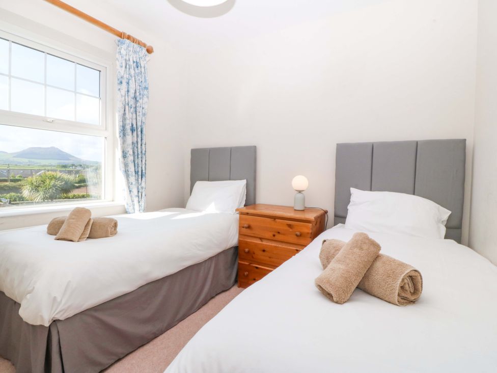 A bedroom with two single beds and a window at Bryniau Morfa Nefyn