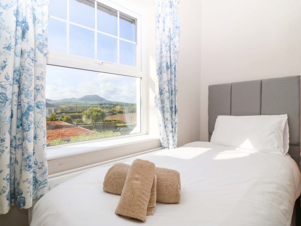 A bedroom with a bed and window at Bryniau Morfa Nefyn